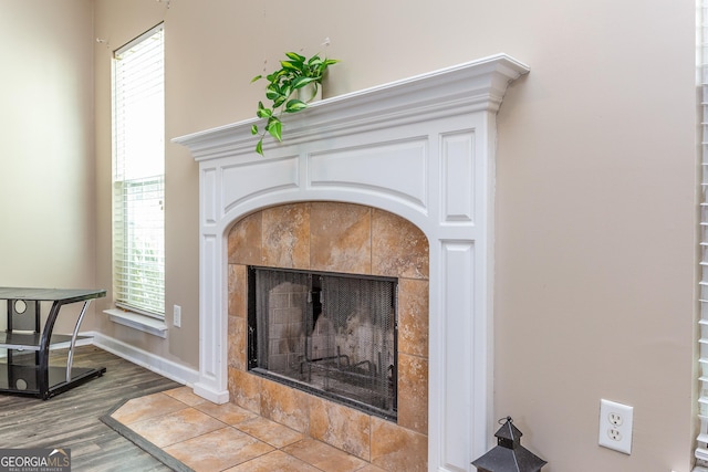 room details featuring baseboards, a tiled fireplace, and wood finished floors