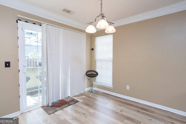 interior space with baseboards, light wood-style flooring, visible vents, and crown molding