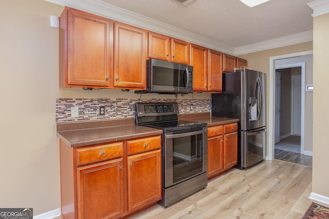 kitchen with light wood finished floors, dark countertops, appliances with stainless steel finishes, crown molding, and backsplash