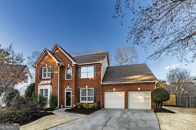 colonial home featuring a garage, concrete driveway, brick siding, and fence