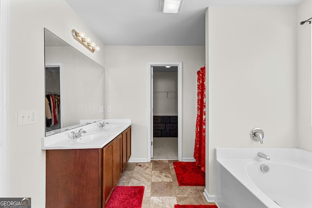 full bathroom featuring a bath, a spacious closet, double vanity, and a sink