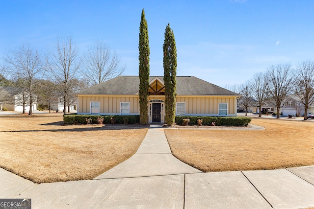 view of front of house with roof with shingles, board and batten siding, and a front yard