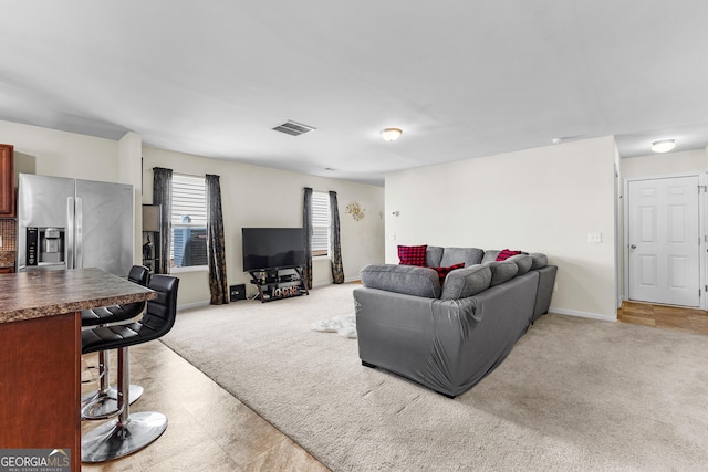 living room with visible vents, light colored carpet, and baseboards