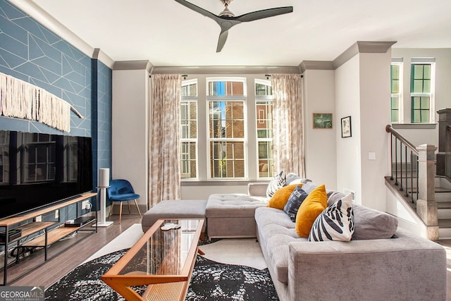 living room featuring ceiling fan, ornamental molding, stairway, and wood finished floors