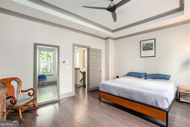 bedroom with visible vents, baseboards, wood-type flooring, ceiling fan, and a tray ceiling