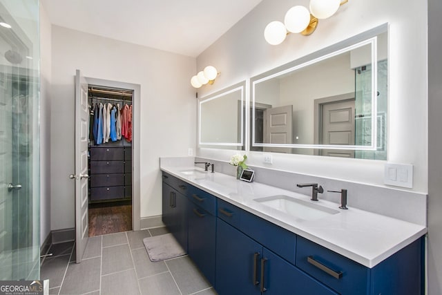 full bath featuring double vanity, an enclosed shower, a sink, and a walk in closet