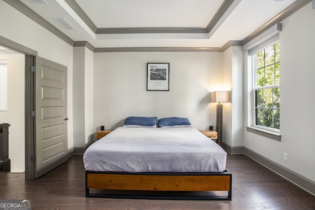 bedroom with baseboards, a tray ceiling, visible vents, and wood finished floors