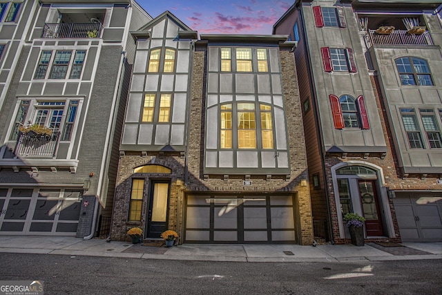 multi unit property with a garage, brick siding, and stucco siding