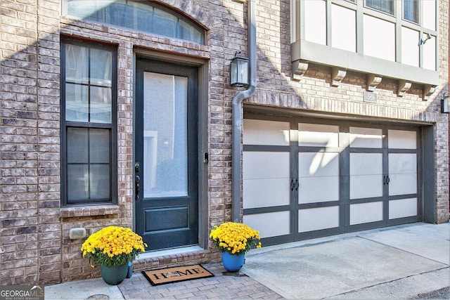 view of exterior entry with a garage and brick siding