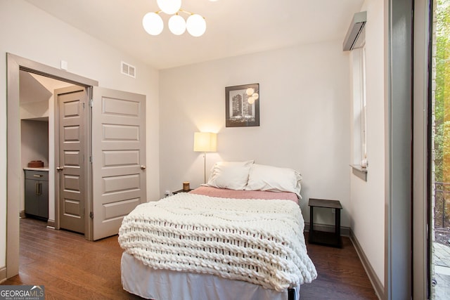 bedroom with a notable chandelier, wood finished floors, visible vents, and baseboards