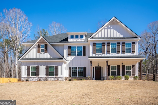 view of front of property with board and batten siding, a front yard, and a shingled roof