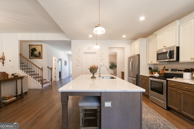 kitchen with dark wood-style floors, appliances with stainless steel finishes, an island with sink, and a sink