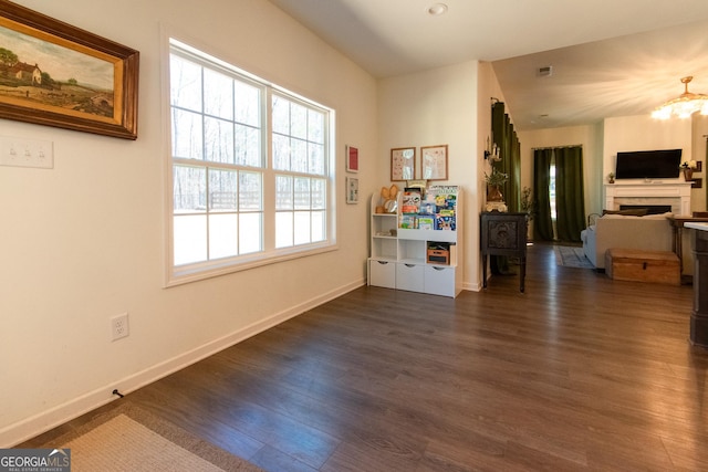 interior space with dark wood-type flooring, a fireplace, visible vents, and baseboards