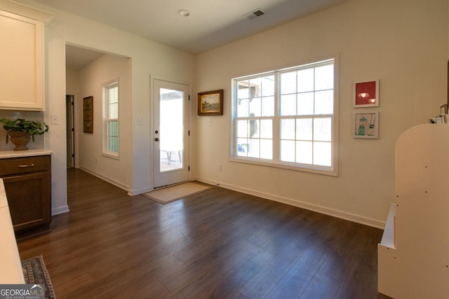 foyer featuring baseboards, visible vents, and dark wood finished floors