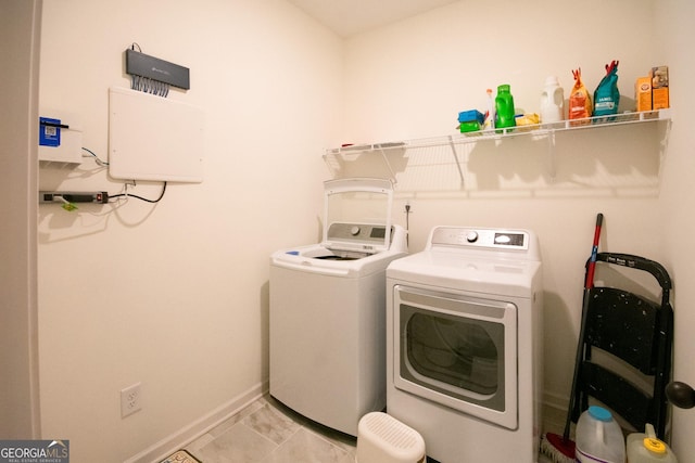 clothes washing area with laundry area, washing machine and dryer, and baseboards