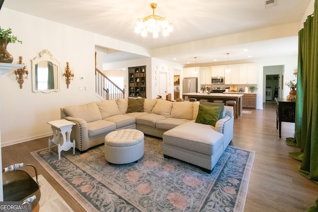 living area featuring recessed lighting, dark wood-style flooring, an inviting chandelier, and stairs