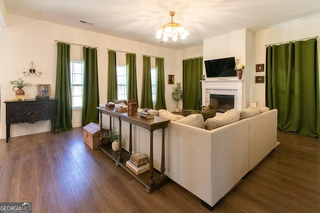 living room with an inviting chandelier, a fireplace, visible vents, and dark wood-type flooring