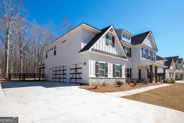 view of front of property with a garage, a shingled roof, fence, concrete driveway, and board and batten siding