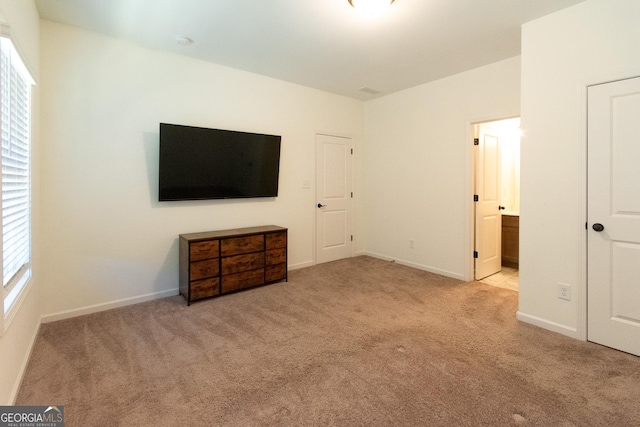 unfurnished bedroom with baseboards, carpet flooring, and connected bathroom