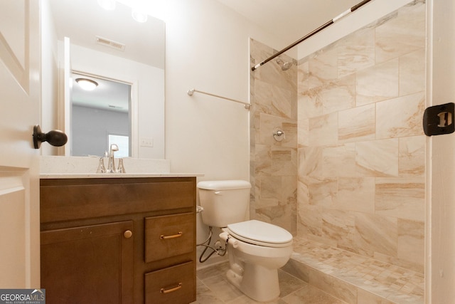 full bathroom with toilet, vanity, visible vents, and a tile shower