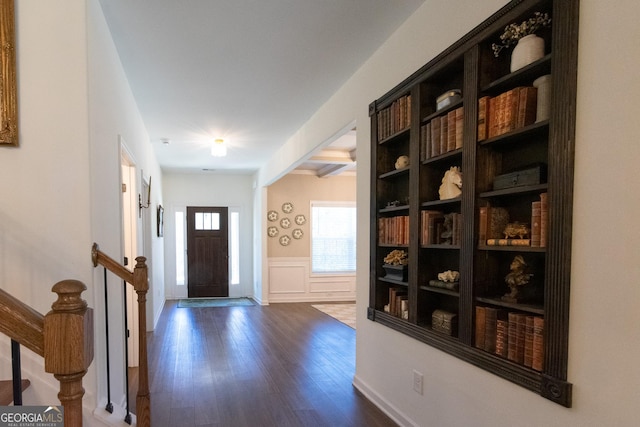 foyer entrance featuring dark wood-style floors, a decorative wall, and a wainscoted wall