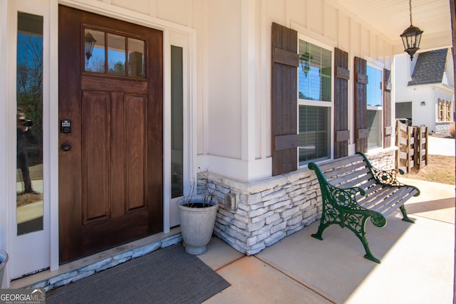 view of exterior entry featuring stone siding and covered porch