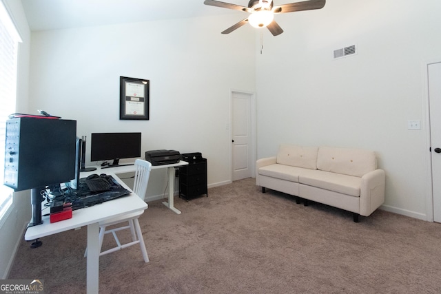 office space with baseboards, visible vents, a ceiling fan, a towering ceiling, and carpet