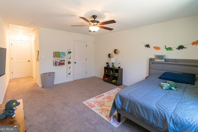 carpeted bedroom featuring attic access, baseboards, and a ceiling fan