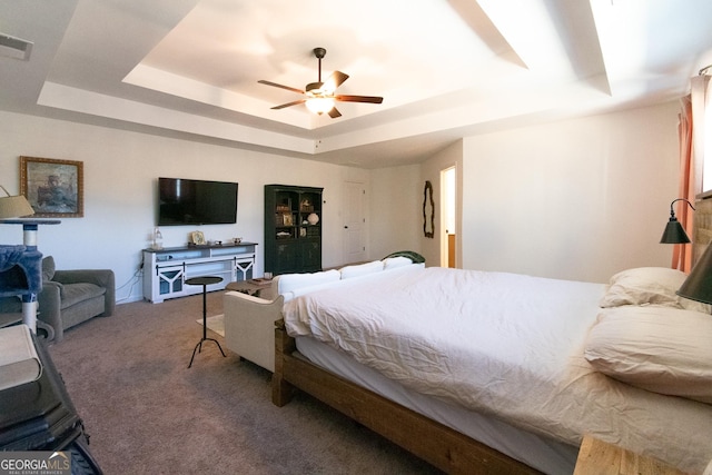 carpeted bedroom with a tray ceiling, visible vents, and ceiling fan