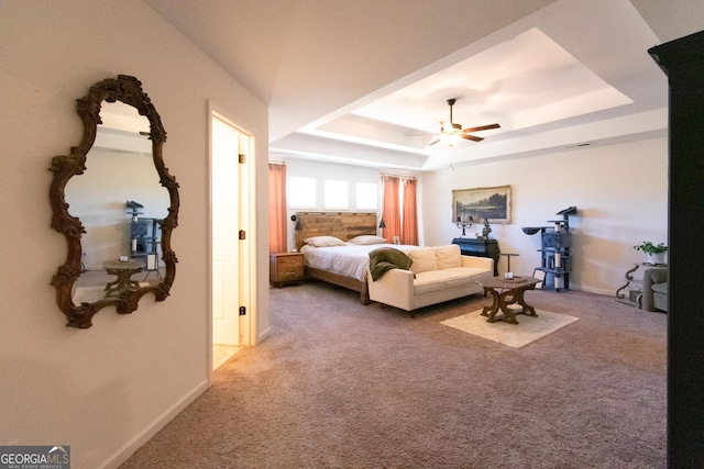 carpeted bedroom featuring a tray ceiling, ceiling fan, and baseboards