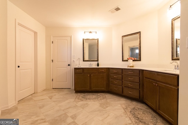 full bath with marble finish floor, visible vents, a sink, and double vanity