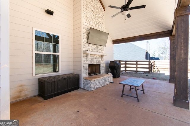 view of patio / terrace with an outdoor stone fireplace, ceiling fan, and fence