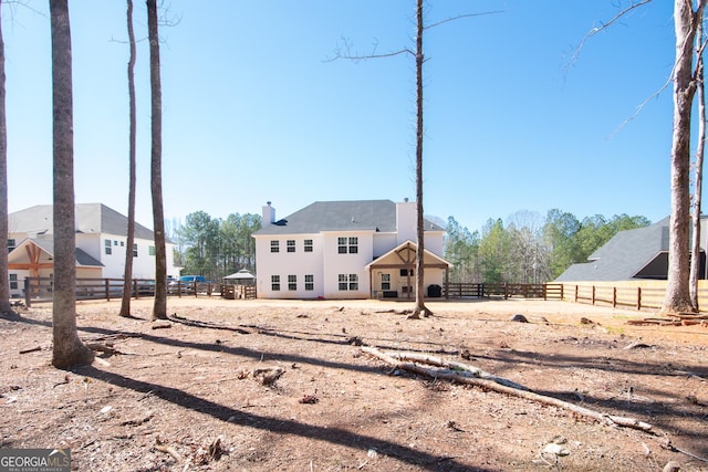 rear view of property with a chimney and fence