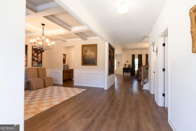 hallway featuring coffered ceiling, dark wood-type flooring, beamed ceiling, a chandelier, and a decorative wall