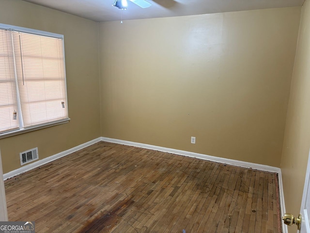 empty room with a ceiling fan, hardwood / wood-style flooring, visible vents, and baseboards