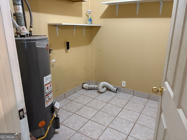 laundry room featuring laundry area, water heater, and light tile patterned floors