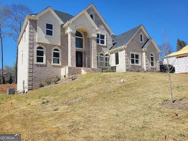 traditional-style house with a front yard, brick siding, and central AC