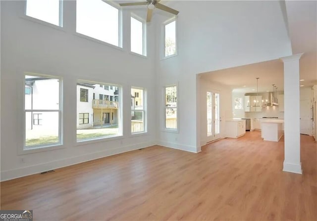 unfurnished living room with visible vents, baseboards, a ceiling fan, light wood-style flooring, and ornate columns