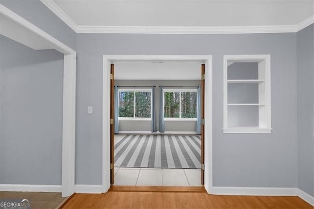 interior space featuring built in shelves, crown molding, and wood finished floors