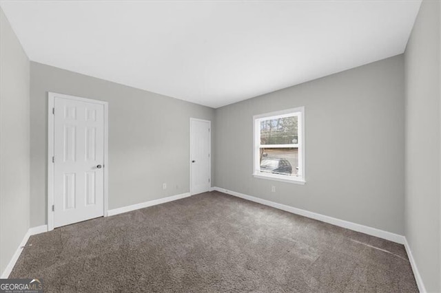 carpeted empty room featuring baseboards