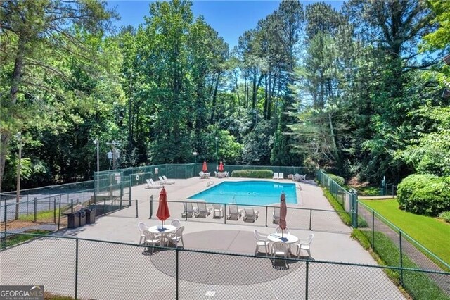 community pool with fence and a patio