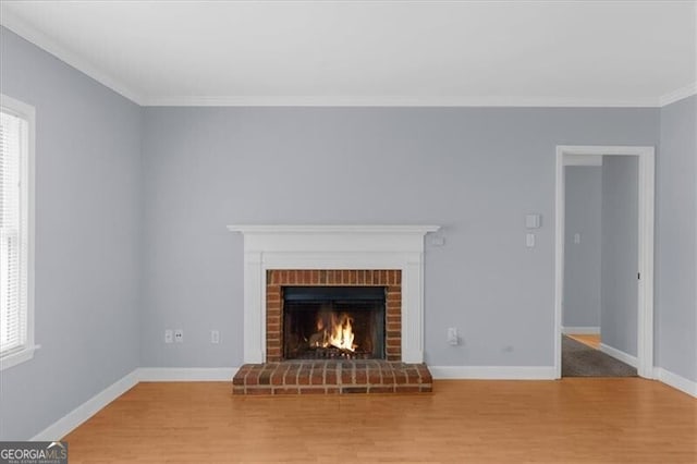 unfurnished living room featuring a brick fireplace, plenty of natural light, and wood finished floors