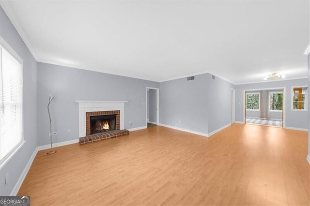 unfurnished living room with light wood-style flooring, a fireplace, visible vents, and ornamental molding