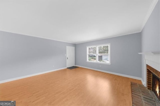 unfurnished living room with a brick fireplace, baseboards, and wood finished floors