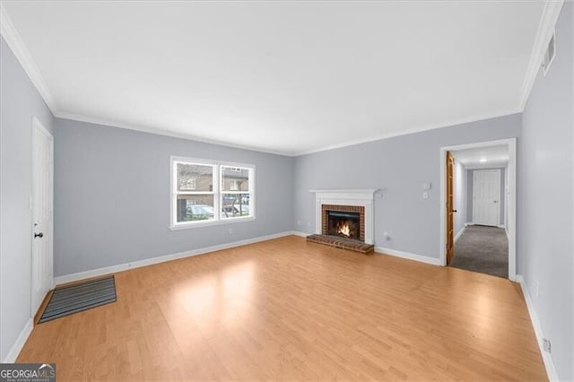 unfurnished living room with crown molding, a fireplace, baseboards, and wood finished floors