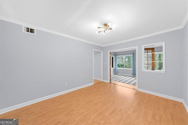 unfurnished room featuring visible vents, baseboards, wood finished floors, and ornamental molding