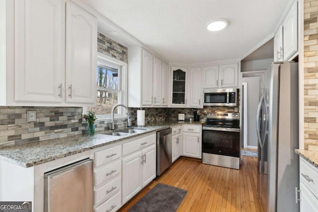 kitchen with decorative backsplash, white cabinetry, stainless steel appliances, and a sink