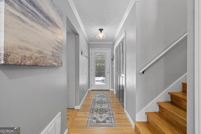 3928 Lake Ct, Gainesville, GA 30501 - entryway with crown molding, visible vents, stairs, light wood-style floors, and baseboards