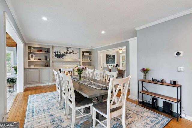 dining space featuring light wood-style floors, recessed lighting, crown molding, and built in features