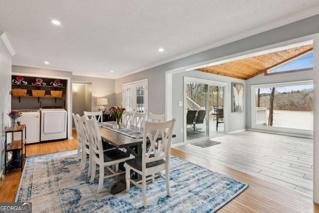 dining area featuring crown molding, washing machine and clothes dryer, lofted ceiling, wood-type flooring, and baseboards